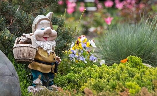 Gnome with basket in spring garden Traditional garden gnome with a wooden basket standing in a colorful German garden